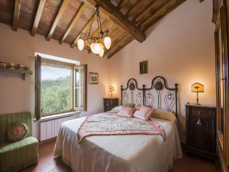 Camera da letto con finestra aperta sulle colline